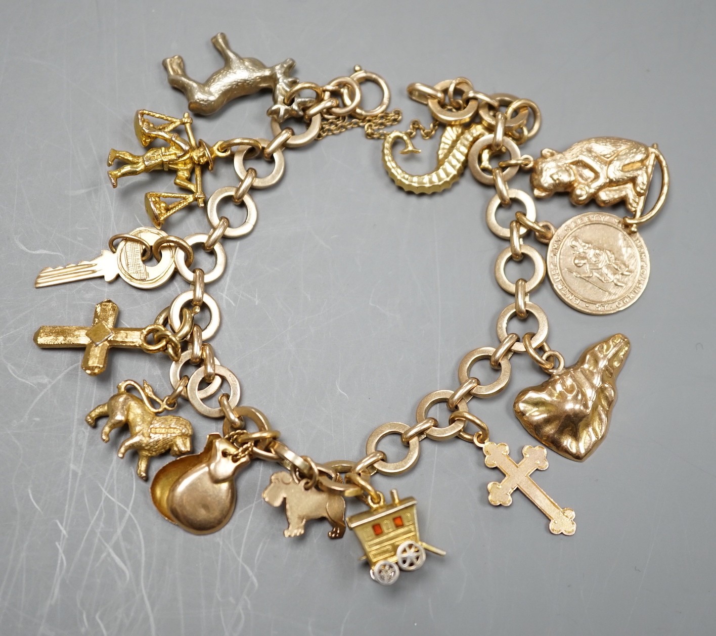 A 9ct gold charm bracelet, hung with assorted charm, including wagon, key, monkey etc. including six 9ct and one 18ct gold, gross weight 33.6 grams.